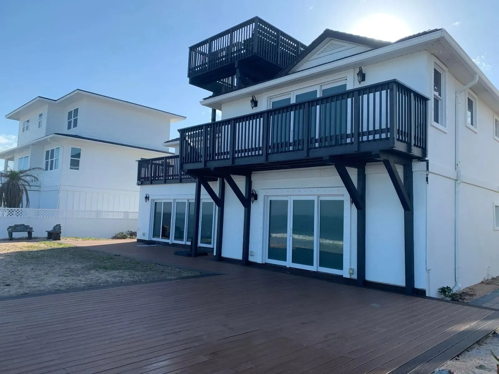 An oceanfront home after, with deck railings, posts and supports painted a dark color