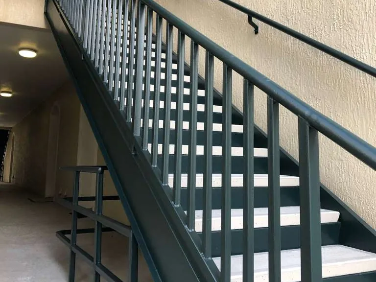 A building stairwell after, with railings, handrails and stringers repainted dark green