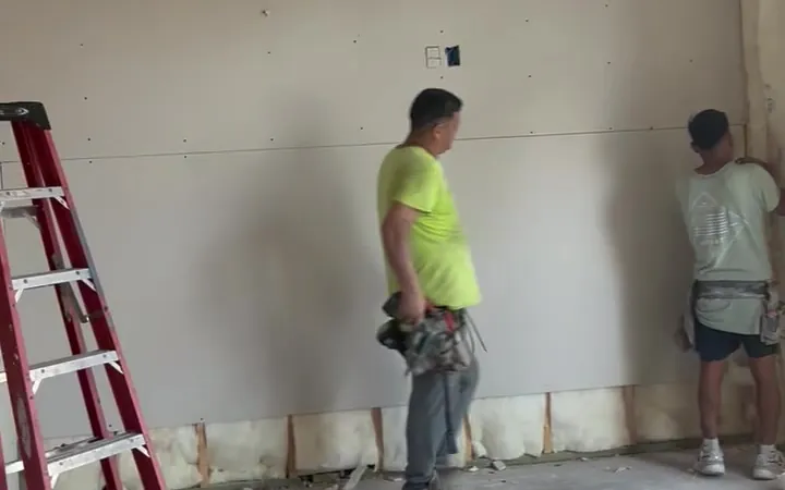 Two Pristine Coastal crew members hanging new drywall