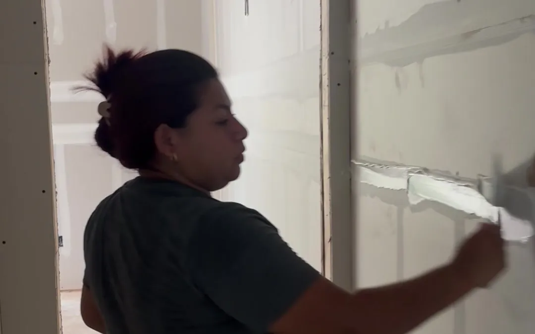 A Pristine Coastal crew member taping a drywall seam at a closet doorway