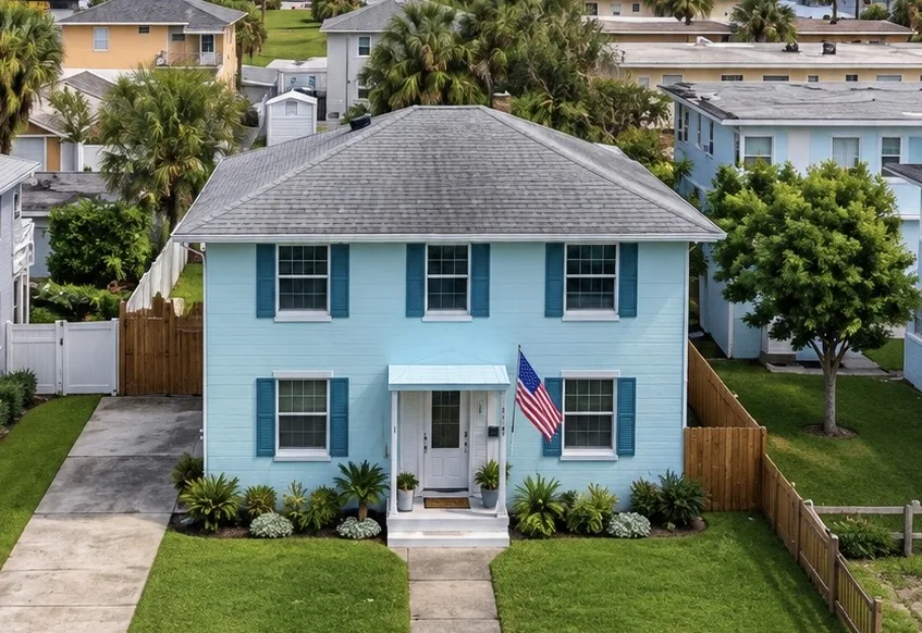 A light blue two-story home with teal shutters on a quiet street in Jacksonville Beach