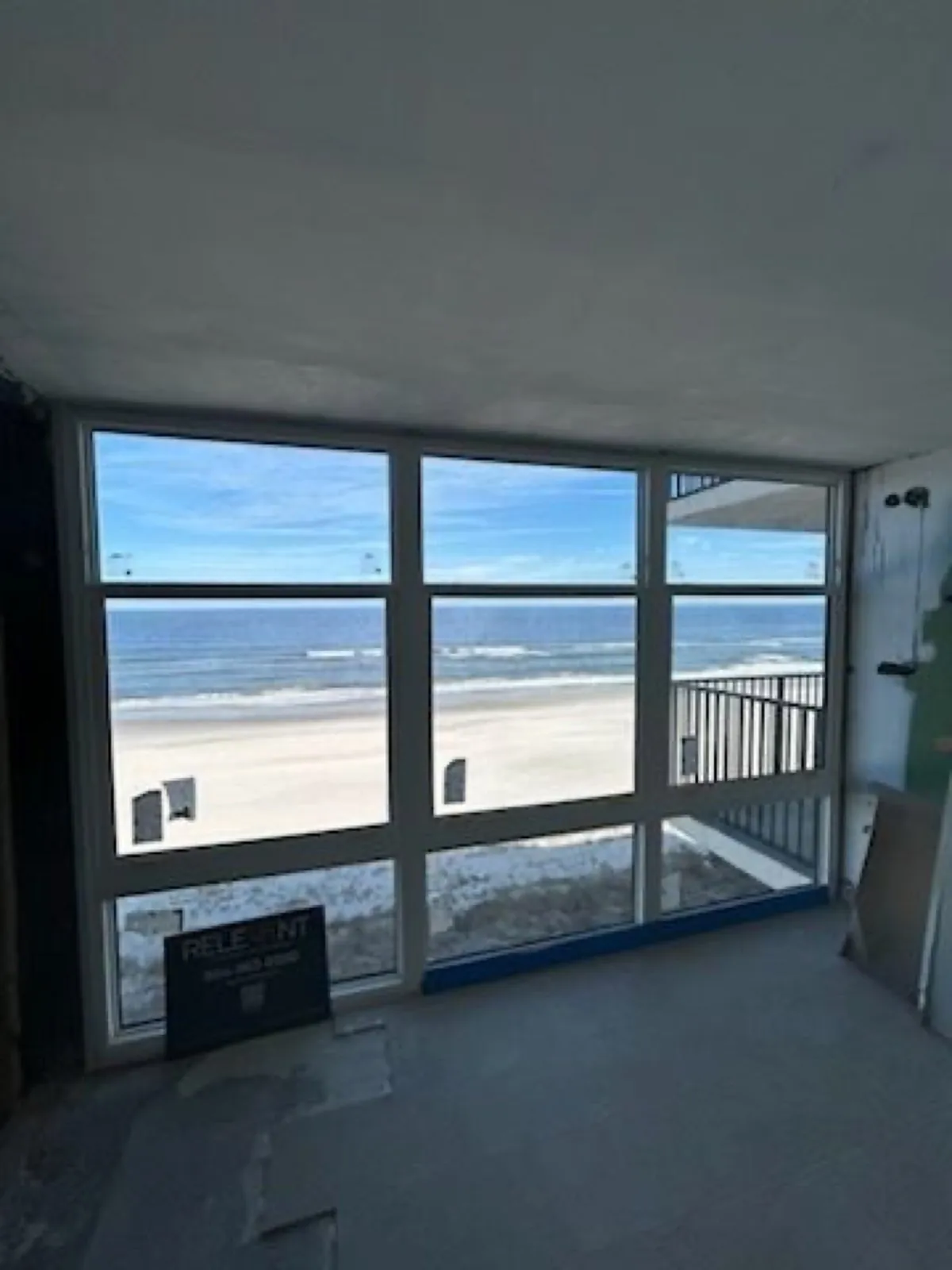 Oceanfront room mid-restoration, with a window wall facing the beach