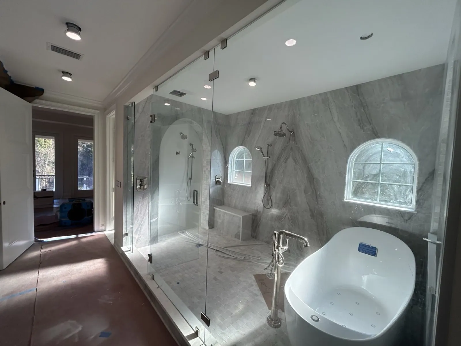 Bathroom with a marble shower, freestanding tub and arched window